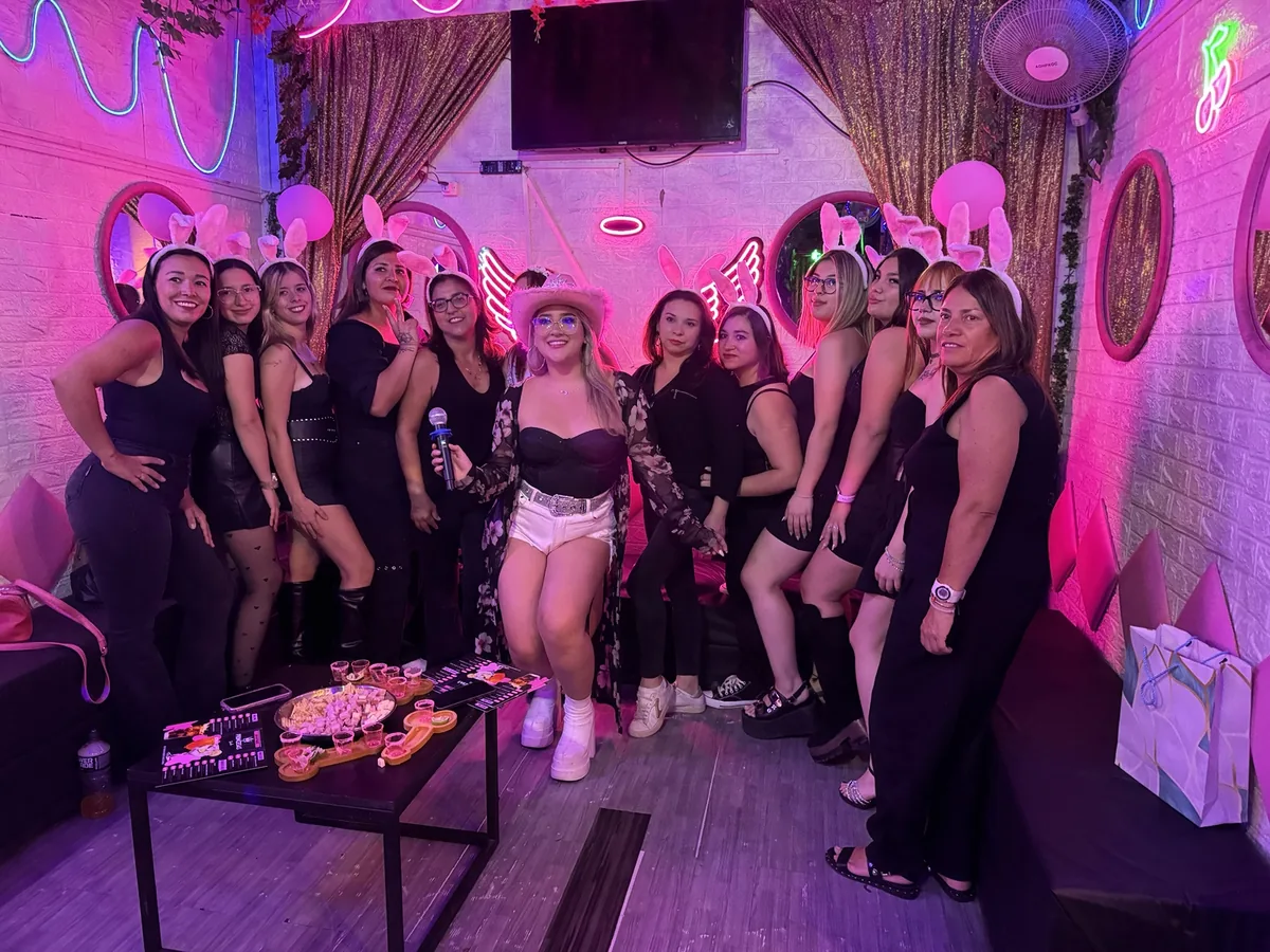 Grupo de amigas celebrando bajo luces de neón rosadas en el Club de Princesas, Santiago Centro