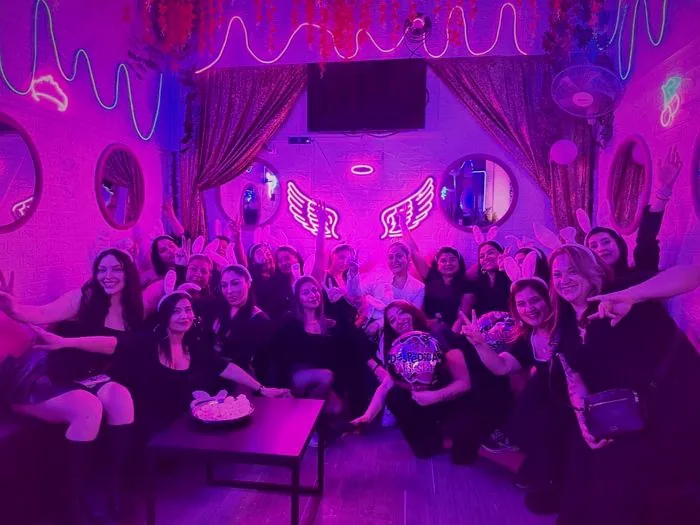Grupo grande de amigas reunidas alrededor de una mesa bajo neones rosados en Santiago
